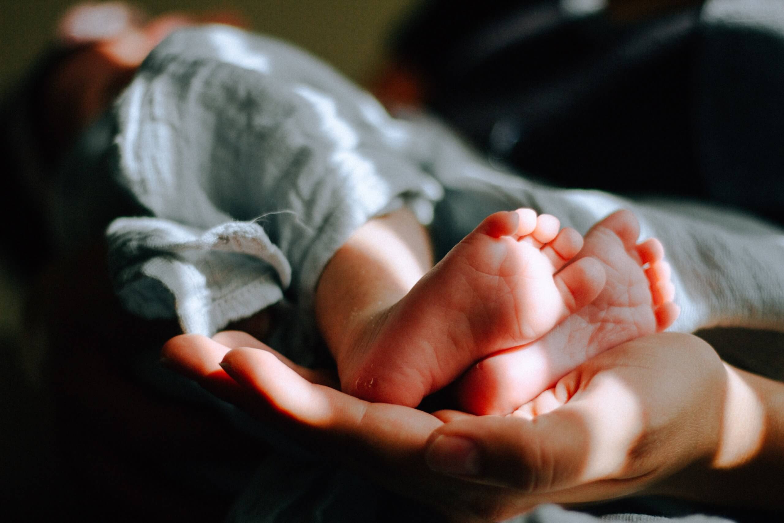 New Born Baby's Feet Cradled by Mother