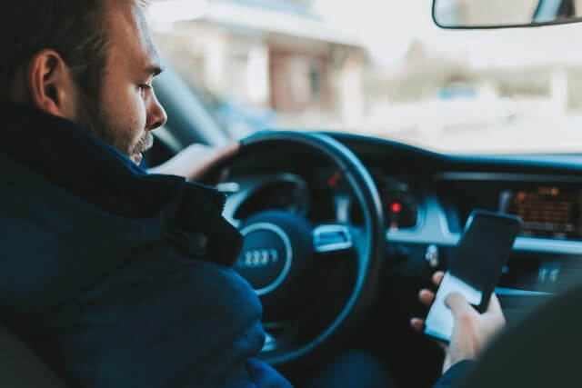 Man Texting on His iPhone While Driving an Audi Luxury Vehicle-min