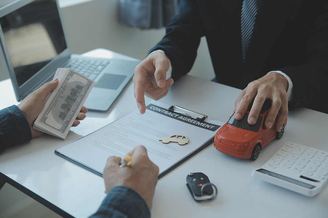 Person reviewing car insurance paperwork and settlement terms with a representative, representing decisions about how much to settle for after a car accident.
