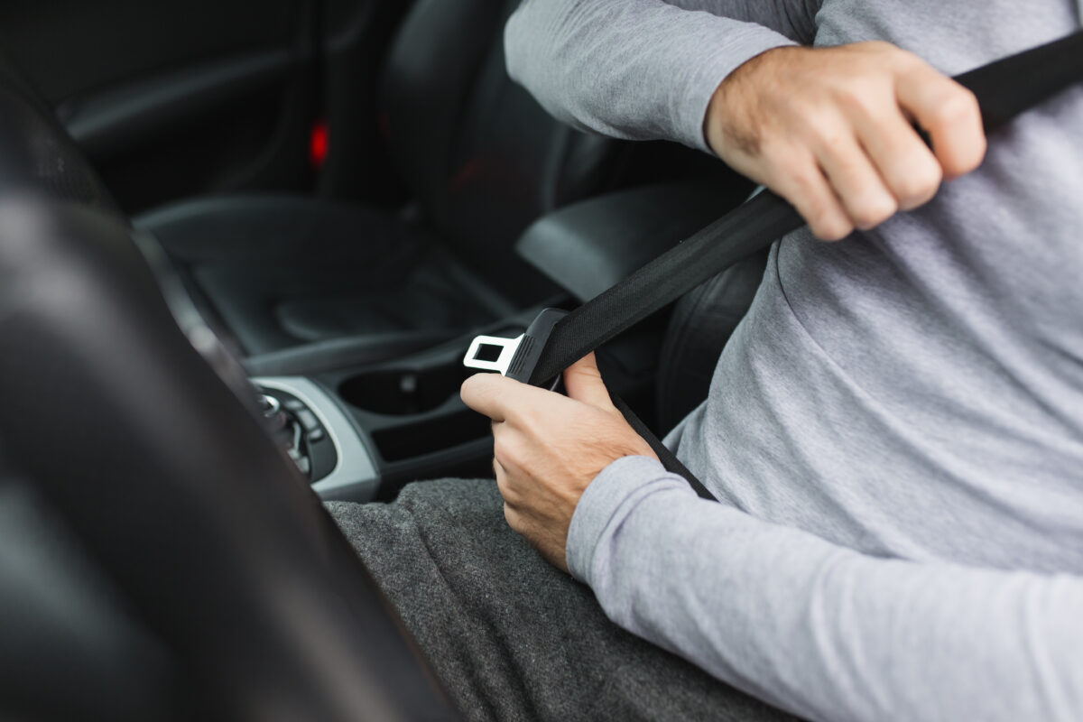 Driver fastening a seat belt, illustrating Michigan seat belt and car seat laws that protect vehicle occupants.