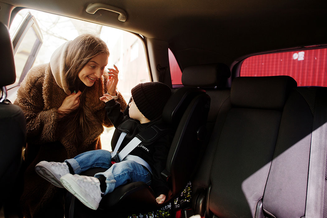 Mother fastening her child into a car seat, highlighting how Michigan car seat laws protect young passengers.