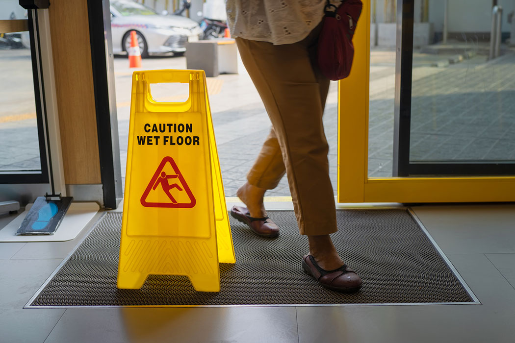 Yellow wet floor warning sign in a retail store aisle, highlighting preventable slip hazards in big-box stores like Meijer or Costco.