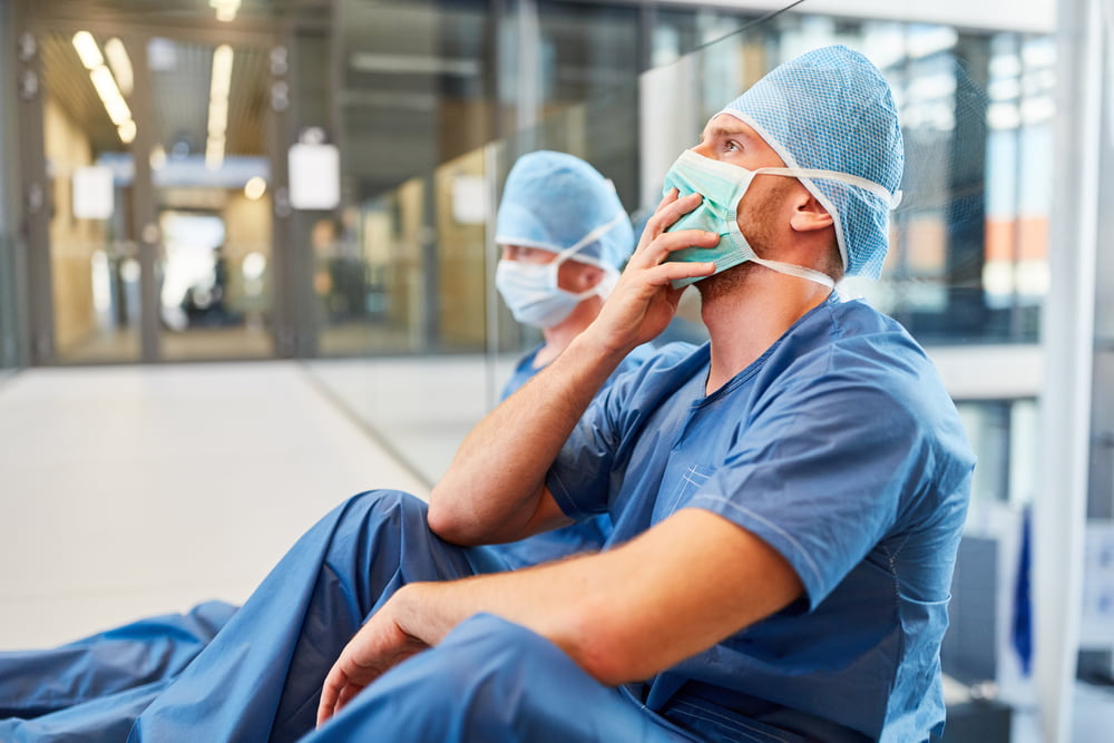 Healthcare workers seated in a hospital corridor appearing concerned after a medical emergency