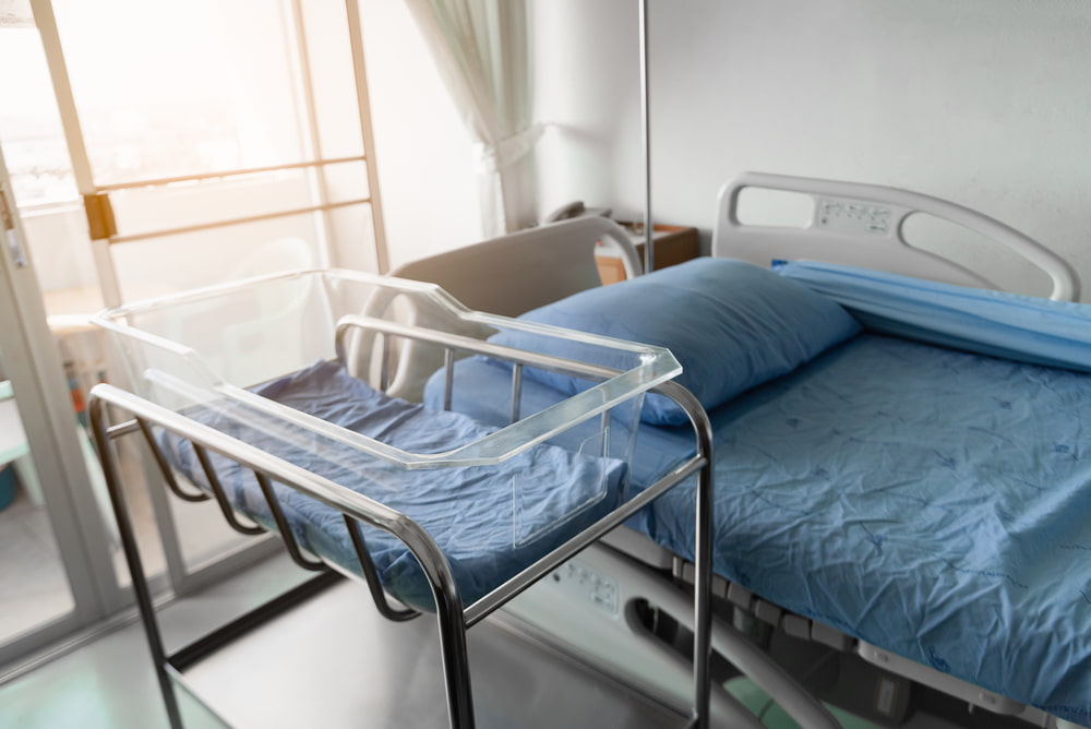 Empty hospital room with a patient bed and medical bassinet