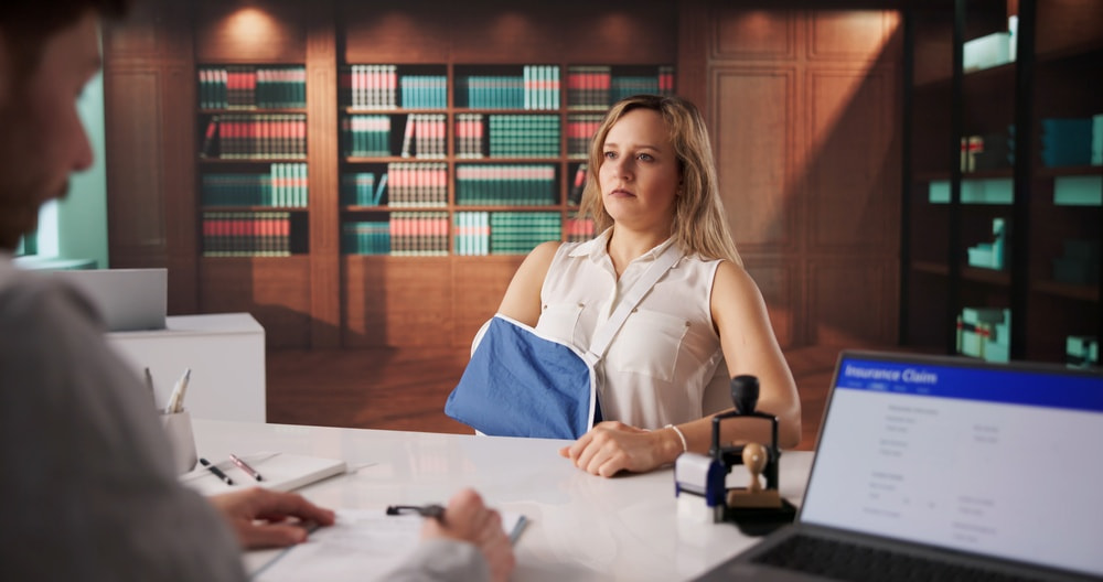 Person with an arm in a sling meeting with a legal professional to discuss a personal injury claim. 