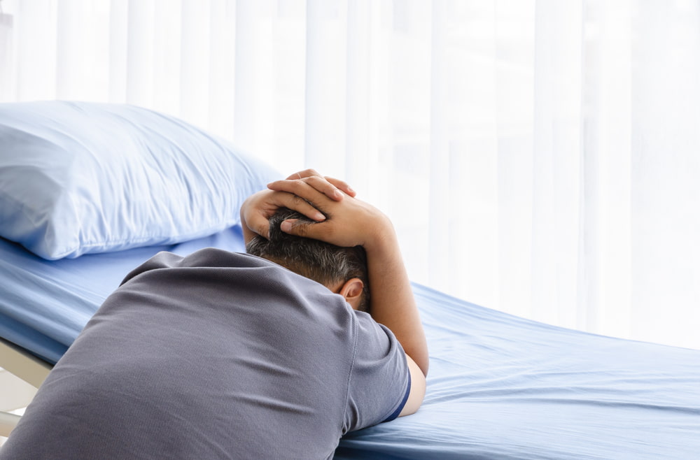 Grieving family member sitting beside a hospital bed after the loss of a loved one in a fatal accident.