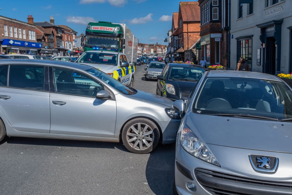 Multiple vehicles involved in a traffic collision at a busy intersection with police responding to the crash scene. 