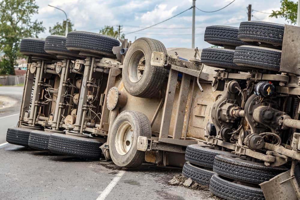 Commercial truck overturned on its side after a rollover accident on a roadway. 