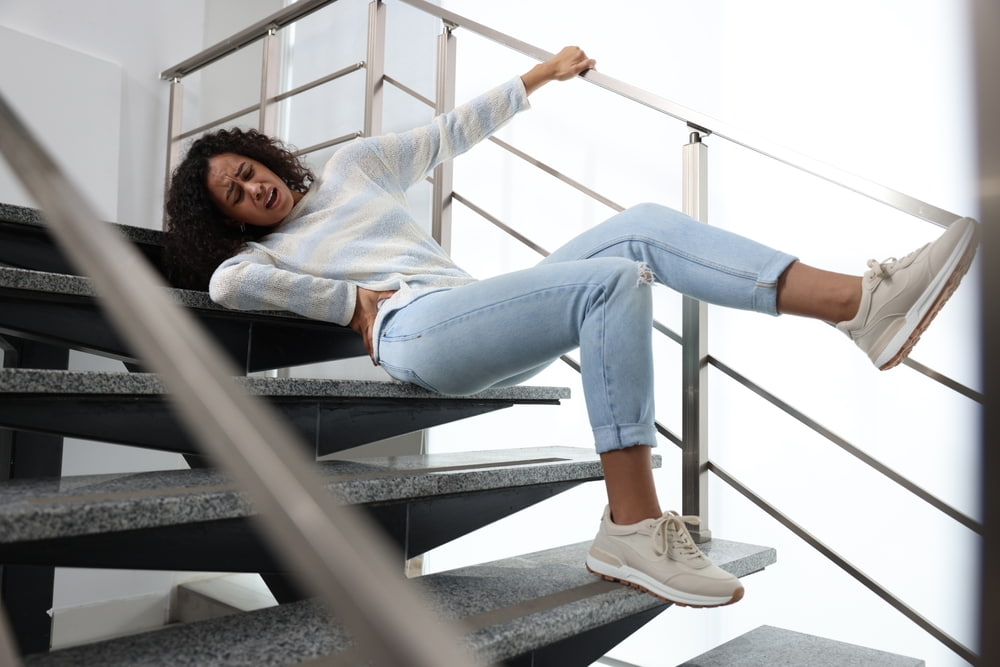 Woman falling down indoor stairs and grabbing the handrail