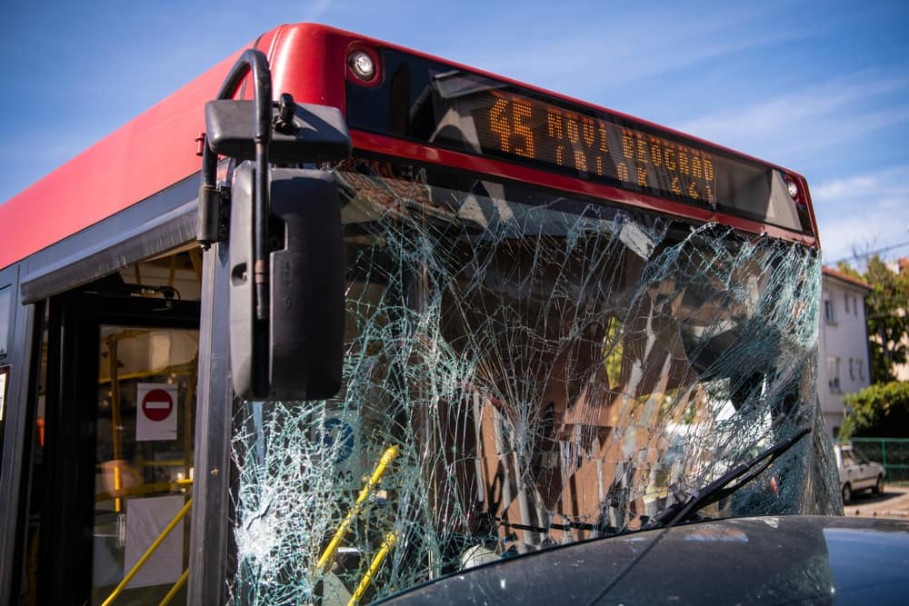 Front of a red city bus with a severely shattered windshield